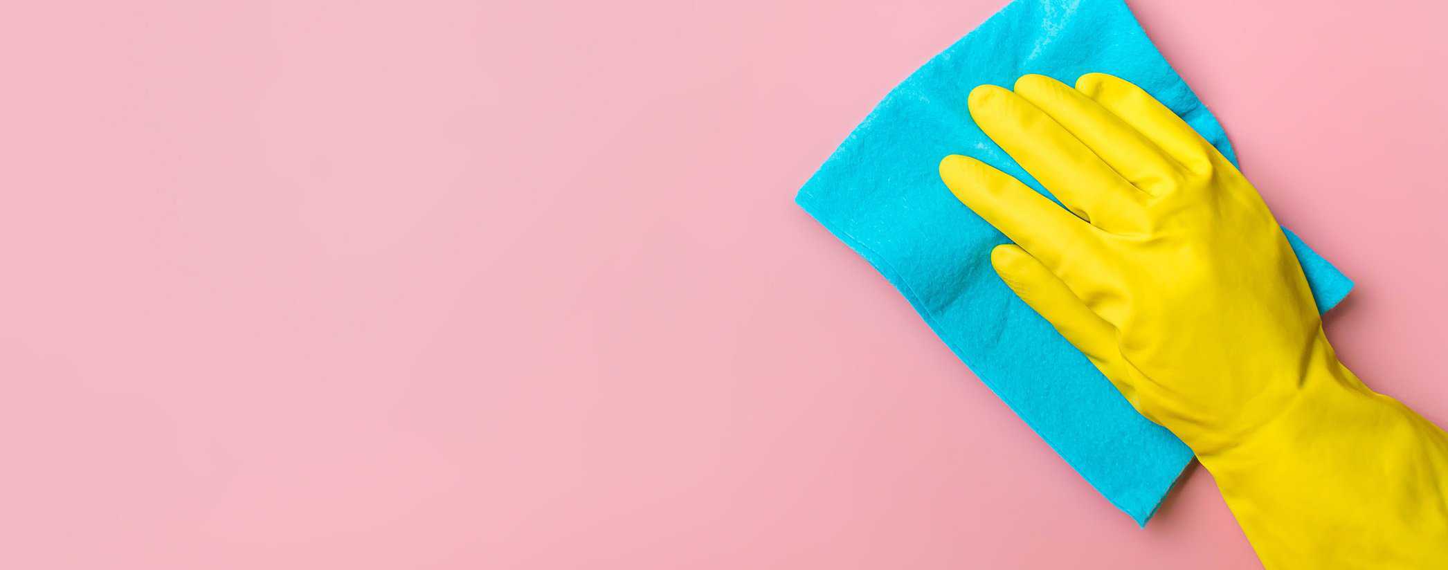 Hand in glove on pink background. Cleaning concept